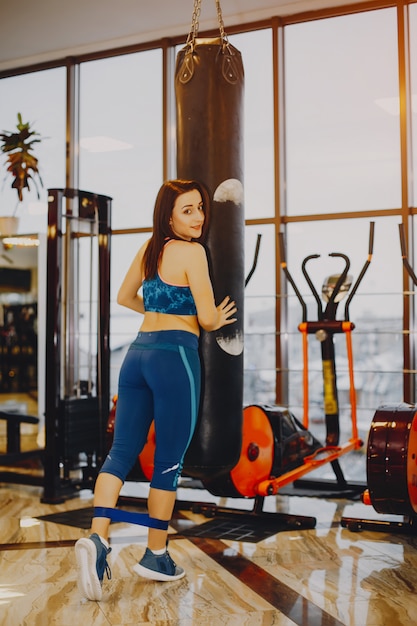 chica joven y bonita en un traje azul se dedica a deportes en el gimnasio