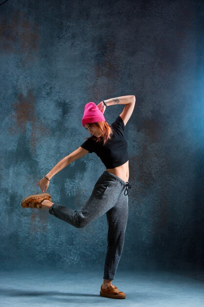 Chica joven break dance sobre fondo de pared.