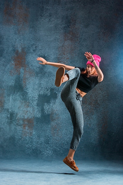 Chica joven break dance sobre fondo de pared.