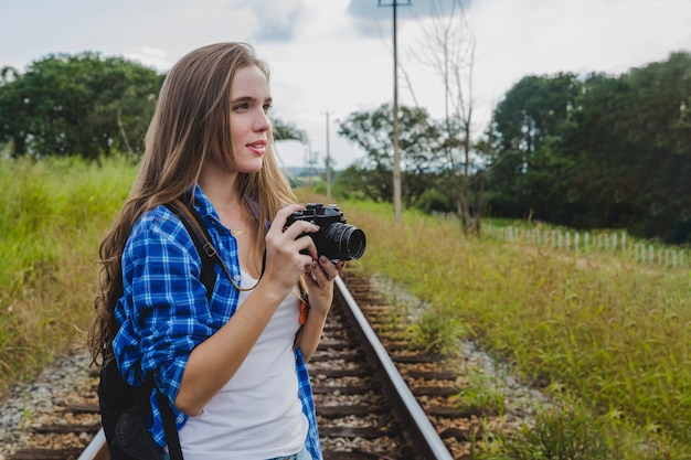 Chica joven con cámara en vías de tren