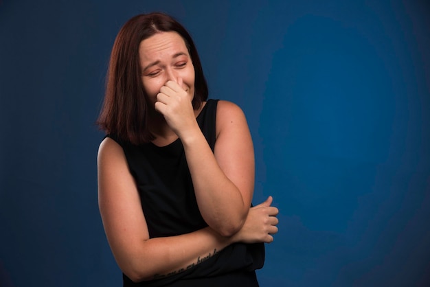 Chica joven en camisa negra manteniendo la respiración.