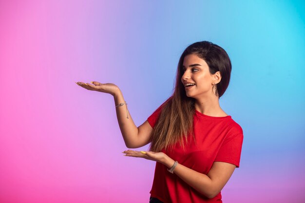 Chica joven en camisa roja mostrando algo.