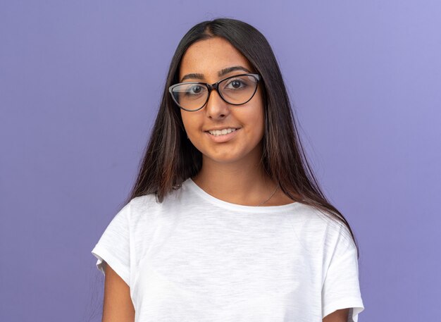 Chica joven en camiseta blanca con gafas mirando a la cámara con una sonrisa en la cara feliz