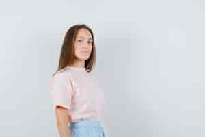 Foto gratuita chica joven en camiseta, falda mirando a cámara y mirando confiada, vista frontal.