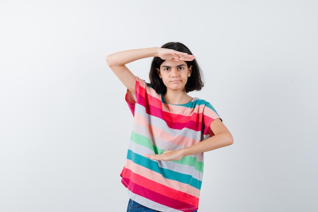 Chica joven en camiseta de rayas de colores mostrando escalas y mirando seria, vista frontal.