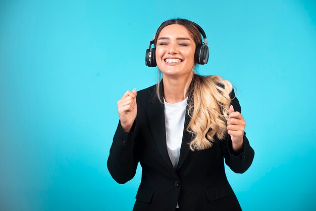 Chica joven en chaqueta negra con auriculares.