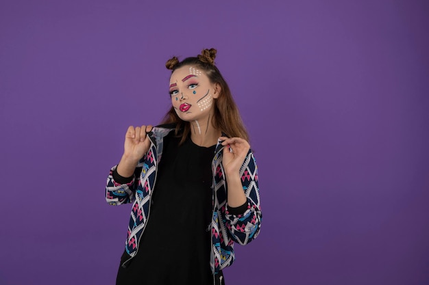 Chica joven confiada con maquillaje de fantasía colorido en bakground púrpura. foto de alta calidad