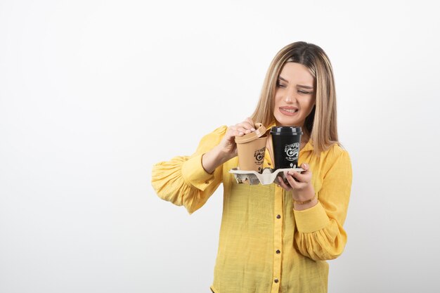 chica joven coning tapas de tazas de café en blanco.