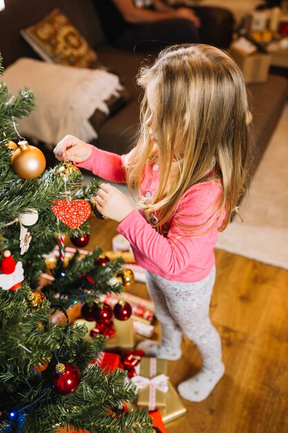 Chica joven decorando árbol de navidad