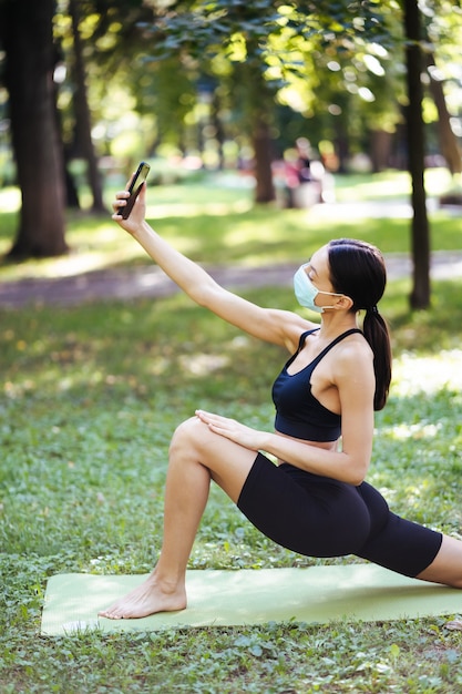 Chica joven deporte tomar selfie en un teléfono inteligente al aire libre en la naturaleza. Concepto de estilo de vida saludable.