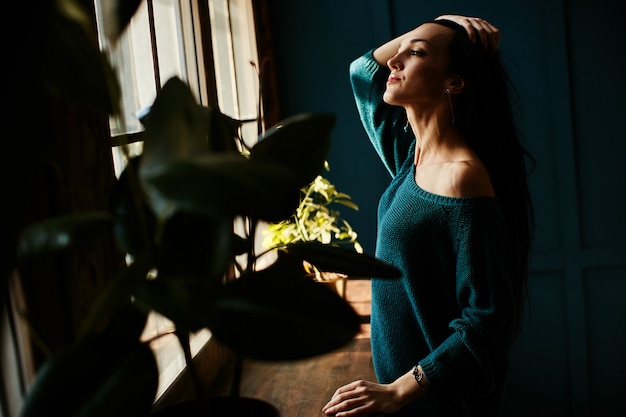 Chica joven disfruta del sol temprano por la ventana