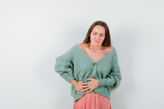 Foto gratuita chica joven con dolor de estómago en géneros de punto, falda y mirando exhausto, vista frontal.