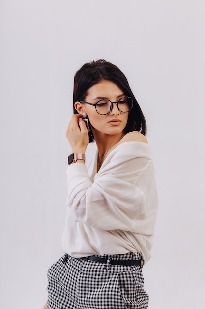 Chica joven elegante atractiva en ropa de negocios posando sobre fondo claro en estudio. Concepto de ropa elegante y sofisticación.