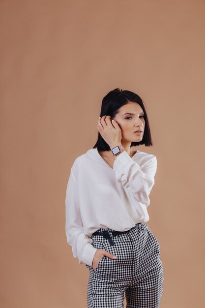 Chica joven elegante atractiva en traje de negocios posando sobre fondo crema. Concepto de ropa elegante y sofisticación.