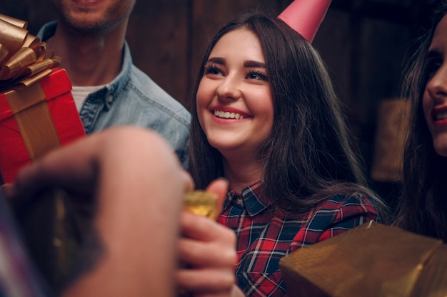 Chica joven emocionada y alegre con un gorro de fiesta sonríe y disfruta de su tiempo en una fiesta de cumpleaños