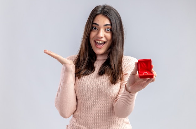 Chica joven emocionada en el día de San Valentín con anillo de bodas extendiendo la mano aislada sobre fondo blanco