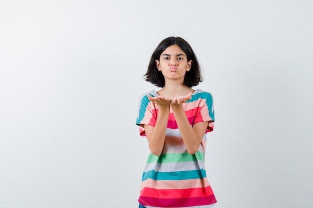 Chica joven enviando besos en camiseta a rayas de colores y luciendo bonita, vista frontal.