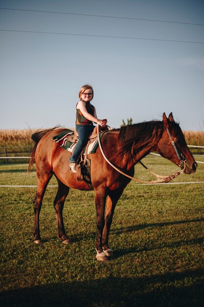 La chica joven está disfrutando de una equitación