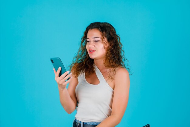 La chica joven está hablando en una llamada de video sobre fondo azul.