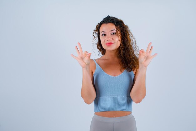 La chica joven está mostrando gestos aceptables en el fondo blanco