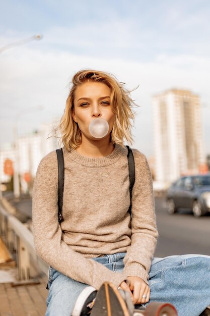 Chica joven con estilo urbano caminando con monopatín. Retrato al aire libre de modelo de mujer deportiva activa. Estilo de vida saludable. Deportes extremos. Look de moda, retrato hipster al aire libre. Close Up retrato de un prett