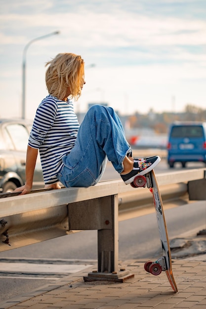 Foto gratuita chica joven con estilo urbano caminando con monopatín. retrato al aire libre de modelo de mujer deportiva activa. estilo de vida saludable. deportes extremos. look de moda, retrato hipster al aire libre. close up retrato de un prett