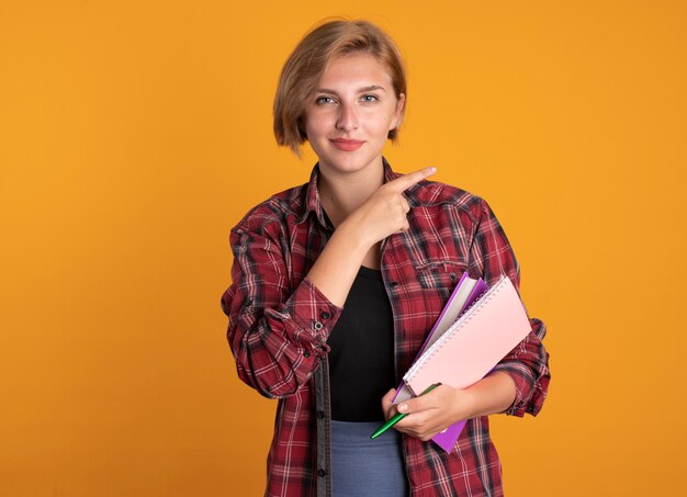 Chica joven estudiante eslava confiada sostiene puntos de cuaderno y bolígrafo en el lateral