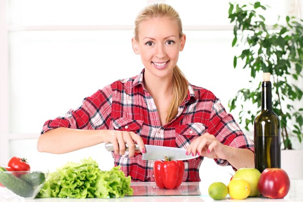 Chica joven y feliz preparando comida saludable