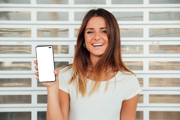 Chica joven feliz que sostiene smartphone