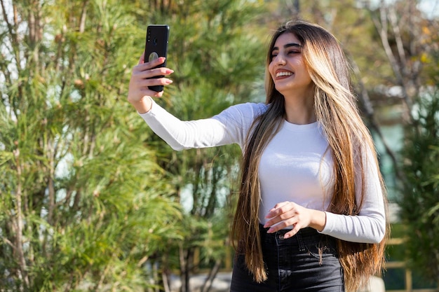 Chica joven feliz sonriendo y tomando selfie Foto de alta calidad