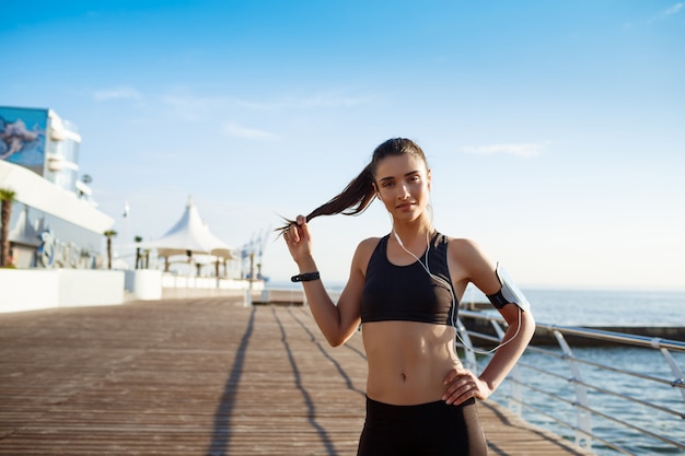 chica joven fitness lista para ejercicios deportivos junto al mar