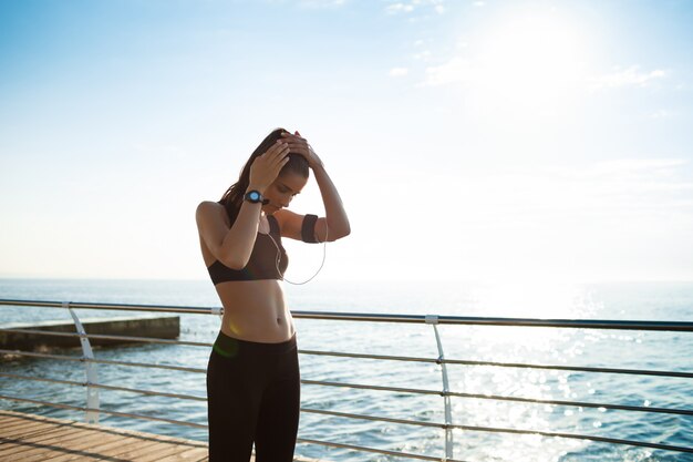 chica joven fitness lista para ejercicios deportivos junto al mar