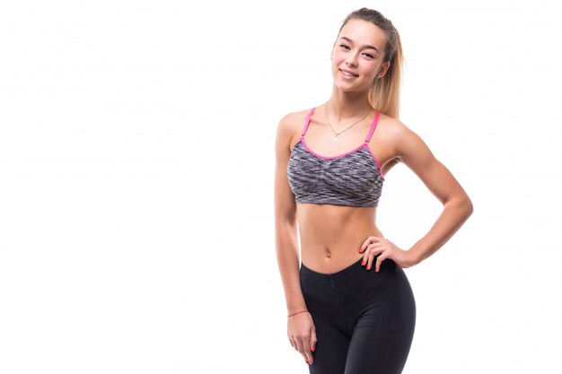 Chica joven fitness muestra su cuerpo muscular en forma fuerte en blanco