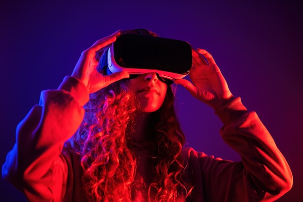 Chica joven en gafas de realidad virtual con iluminación azul y roja en la habitación. Entretenimiento en casa
