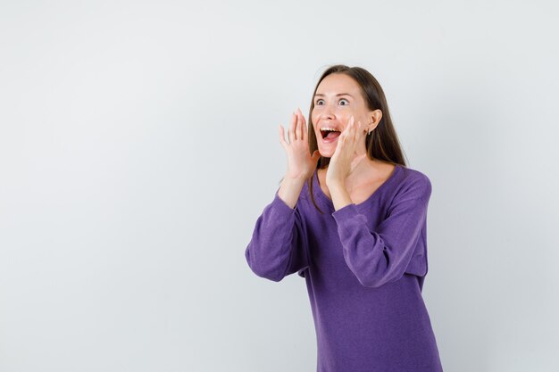 Chica joven gritando o anunciando algo en la vista frontal de la camisa violeta.