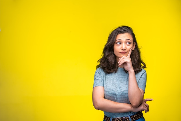 La chica joven hace la cara y los ojos pensativos.