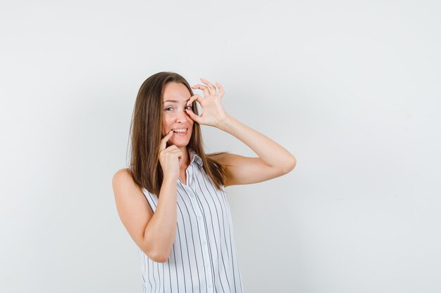 Chica joven haciendo gesto bien en camiseta y mirando complacido. vista frontal.