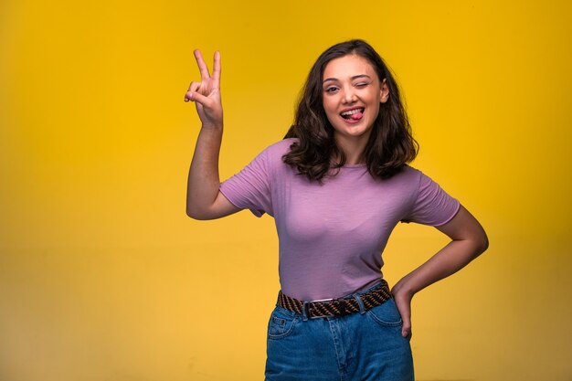 Chica joven haciendo el signo de la amistad en la mano y con la lengua fuera.