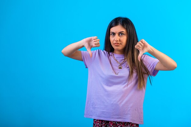 Chica joven haciendo signo de pulgar hacia abajo.