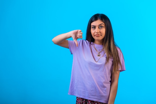 Chica joven haciendo el signo de los pulgares hacia abajo con una mano.