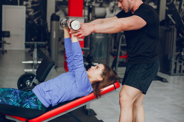 Una chica joven y hermosa con su novio entrenando en un gimnasio