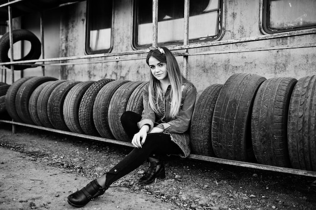 Foto gratuita chica joven hipster en chaqueta de jeans y pañuelo en la cabeza en la zona de montaje de neumáticos