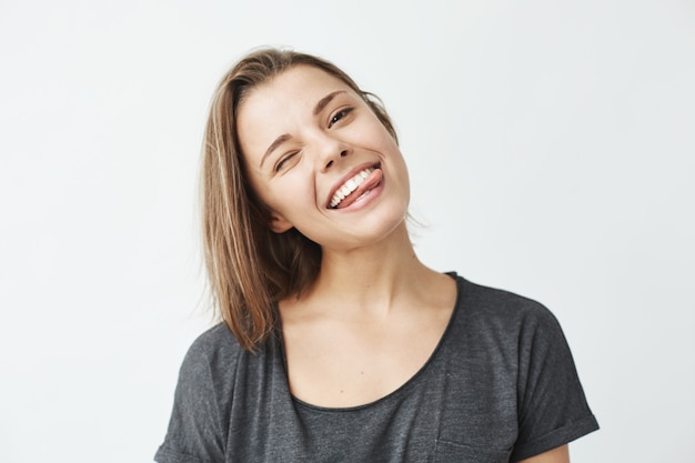 Chica joven linda divertida que sonríe guiñando un ojo mostrando la lengua.