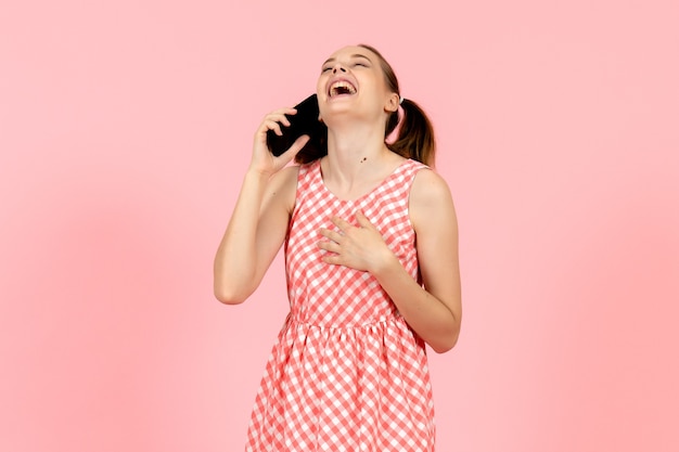 Chica joven en lindo vestido brillante hablando por teléfono y riendo en rosa