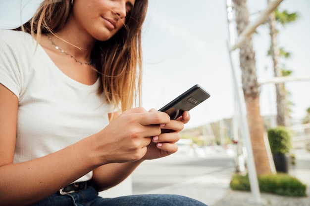 Foto gratuita chica joven con mensajes de texto de teléfono inteligente