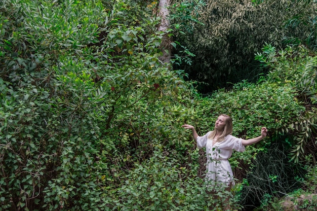 Chica joven mirando hacia arriba con la naturaleza de fondo