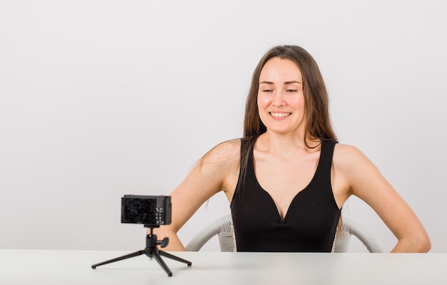 Foto gratuita la chica joven está mirando la cámara pequeña sonriendo en el fondo blanco