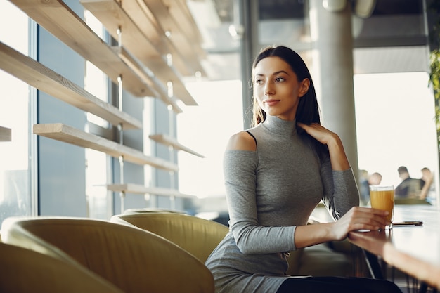 Chica joven de la moda que se sienta en un café