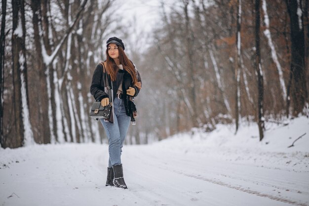 Chica joven modelo caminando en el parque de invierno
