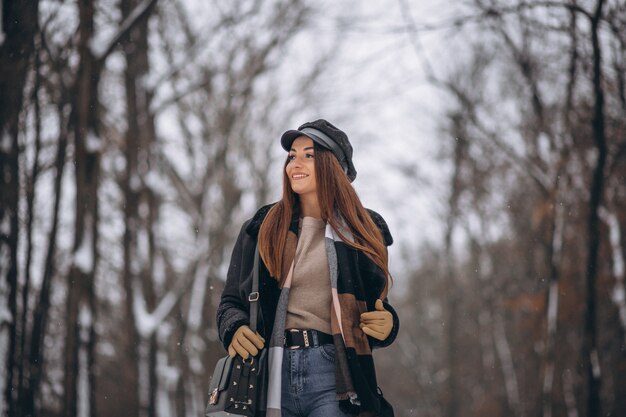 Chica joven modelo caminando en el parque de invierno